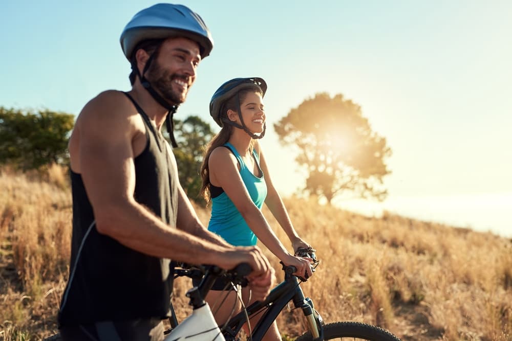 Happy couple, nature and cycling in the mountains for fitness and exercise together.