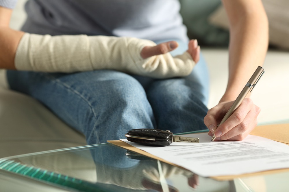 an injured woman signing insurance forms