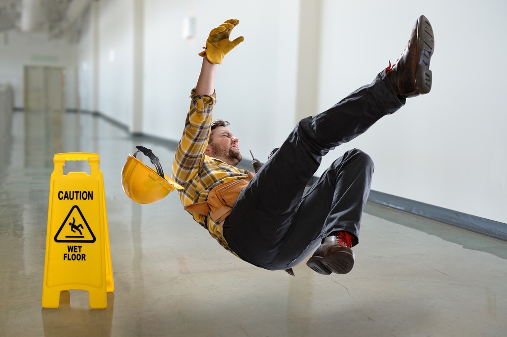 Un trabajador de construcción resbala y cae en un piso mojado